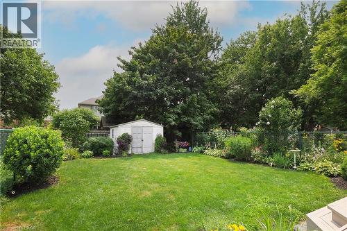 Expansive backyard featuring a manicured lawn, established garden beds, mature trees, and a functional storage shed - 218 Inverhuron Crescent Unit# A, Waterloo, ON - Outdoor