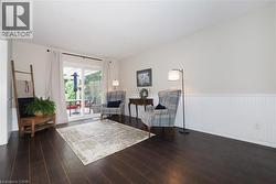Spacious room featuring dark wood-finish flooring, white walls, and wainscoting - 