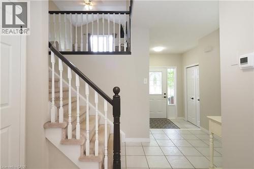 Foyer featuring a carpeted staircase with white balusters and a dark wood handrail, white tiled flooring, and a front entry door with decorative glass inserts - 218 Inverhuron Crescent Unit# A, Waterloo, ON - Indoor Photo Showing Other Room