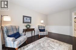 Spacious room featuring dark wood-finish flooring, white wainscoting, and neutral-toned walls - 