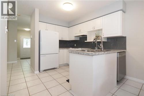 Modern kitchen featuring white cabinetry, a stainless steel dishwasher, and a dual-basin sink with a pull-down faucet - 218 Inverhuron Crescent Unit# A, Waterloo, ON - Indoor Photo Showing Kitchen