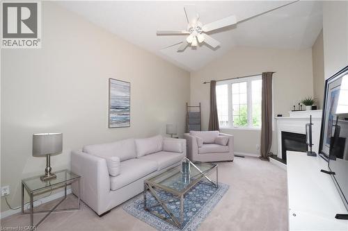 Living room featuring a vaulted ceiling with a ceiling fan, a fireplace with a white mantel, and a multi-pane window with dark drapery - 218 Inverhuron Crescent Unit# A, Waterloo, ON - Indoor Photo Showing Living Room With Fireplace