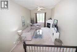 Living area featuring vaulted ceilings, a ceiling fan, and a fireplace with a white mantel - 