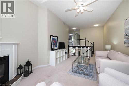 Living area featuring a fireplace with a white mantel, high ceilings, a ceiling fan, and carpet flooring - 218 Inverhuron Crescent Unit# A, Waterloo, ON - Indoor Photo Showing Living Room With Fireplace