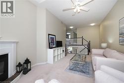 Living area featuring a fireplace with a white mantel, high ceilings, a ceiling fan, and carpet flooring - 