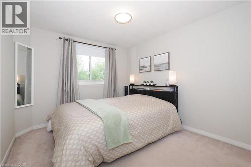 Carpeted bedroom featuring a large window with drapes, a flush-mount ceiling light, and light-toned walls - 218 Inverhuron Crescent Unit# A, Waterloo, ON - Indoor Photo Showing Bedroom