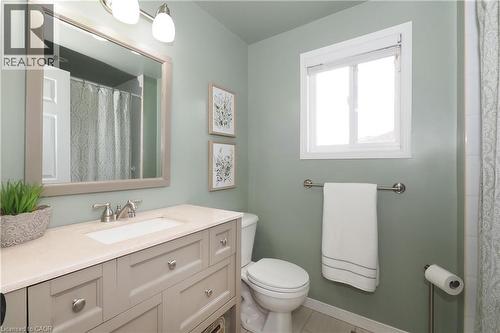 Bathroom featuring a single vanity with a neutral-toned countertop and integrated sink, brushed nickel faucet, a framed mirror, and a window with white trim - 218 Inverhuron Crescent Unit# A, Waterloo, ON - Indoor Photo Showing Bathroom
