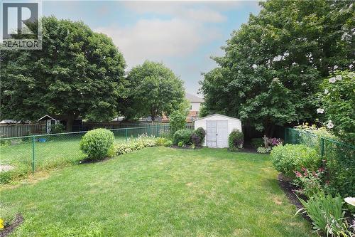 Expansive backyard featuring a manicured lawn, established garden beds, and a white storage shed - 218 Inverhuron Crescent Unit# A, Waterloo, ON - Outdoor