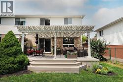 Backyard deck with a white painted pergola, multiple steps, and surrounding green landscaping - 