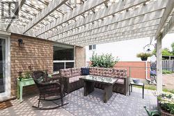 Expansive patio featuring a white pergola structure, brick exterior, and a sliding glass door - 