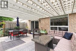 Exterior patio featuring an open lattice pergola, brick facade, sliding glass doors, and a large picture window - 