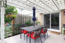 Outdoor patio featuring a white pergola, brick exterior, and sliding glass door - 