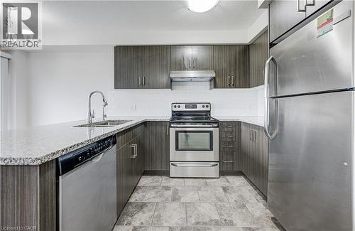 Modern kitchen featuring wood-finish cabinetry, granite-style countertops, stainless steel appliances, a subway tile backsplash, and tile flooring - 823 Paris Boulevard, Waterloo, ON - Indoor Photo Showing Kitchen With Stainless Steel Kitchen With Double Sink With Upgraded Kitchen
