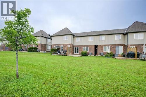 Expansive green lawn with rear townhouse exteriors featuring brick and siding finishes, multiple windows, and sliding glass doors leading to outdoor decks - 823 Paris Boulevard, Waterloo, ON - Outdoor