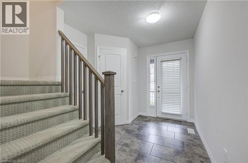 Foyer with ceramic tile flooring, a white exterior door with an integrated blind, and a staircase featuring carpeted treads and a wood-finish railing - 823 Paris Boulevard, Waterloo, ON - Indoor Photo Showing Other Room