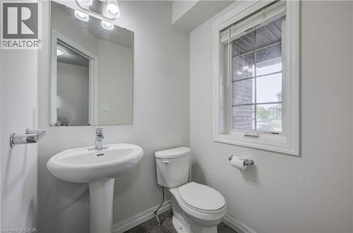 Pedestal sink with chrome faucet, large rectangular mirror, and an overhead vanity light fixture - 823 Paris Boulevard, Waterloo, ON - Indoor Photo Showing Bathroom