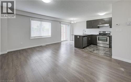 Open concept living space featuring wood-finish flooring, a kitchen island with seating, stainless steel appliances, white subway tile backsplash, and sliding glass door access to an exterior area - 823 Paris Boulevard, Waterloo, ON - Indoor Photo Showing Kitchen