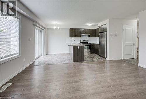 Open-concept living space featuring wood-finish flooring, a kitchen island with a stainless steel sink, dark wood-finish cabinetry, and stainless steel appliances - 823 Paris Boulevard, Waterloo, ON - Indoor Photo Showing Kitchen