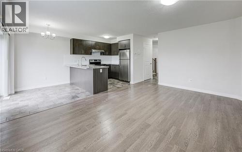 Open-concept living area with wood-finish flooring, a kitchen island, stainless steel appliances, dark wood cabinetry, and a sliding glass door - 823 Paris Boulevard, Waterloo, ON - Indoor Photo Showing Kitchen