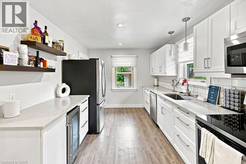 Contemporary kitchen featuring white cabinetry, light-toned countertops, a subway tile backsplash, stainless steel appliances, and wood-finish flooring - 67 Weber Street S, Waterloo, ON - Indoor Photo Showing Kitchen