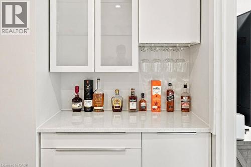 Built-in wet bar featuring white cabinetry, frosted glass cabinet doors, a light-toned countertop, and integrated stemware storage - 67 Weber Street S, Waterloo, ON - Indoor Photo Showing Other Room