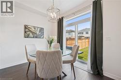 Dining area featuring dark wood-finish flooring, white baseboards, and a contemporary geometric chandelier - 