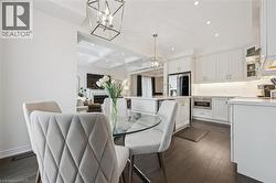 Open-concept kitchen with dark wood-finish flooring, white cabinetry, integrated stainless steel appliances, and recessed lighting - 