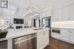Contemporary kitchen featuring an island with a double sink, stainless steel dishwasher, and white countertops - 