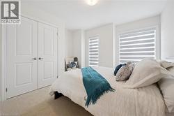 Spacious bedroom featuring light-colored carpeting, two paneled doors, and two windows with horizontal blinds - 
