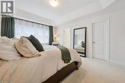 Bedroom featuring a tray ceiling and broad window with sheer and blackout drapes - 