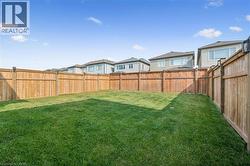 Spacious backyard featuring a full wood privacy fence, expansive lawn, and post-mounted lighting - 