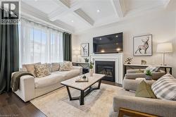Living room featuring hardwood flooring, a fireplace with a white mantel, and a coffered ceiling - 