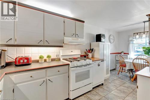 Kitchen featuring white cabinetry, grey countertops with red trim, a white tile backsplash, and a white gas range - 98 Belwood Crescent, Kitchener, ON - Indoor Photo Showing Kitchen