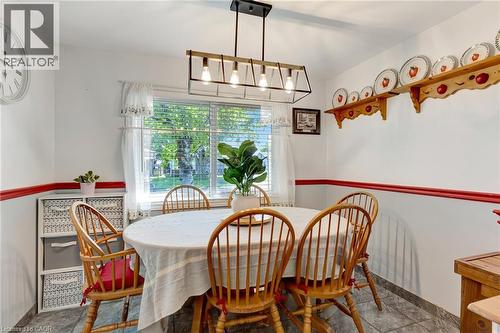 Dining area featuring a contemporary linear chandelier, tiled flooring, and a large window with natural light - 98 Belwood Crescent, Kitchener, ON - Indoor Photo Showing Dining Room