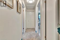 Hallway featuring light-colored carpeting, white walls, and a round flush-mount ceiling light - 