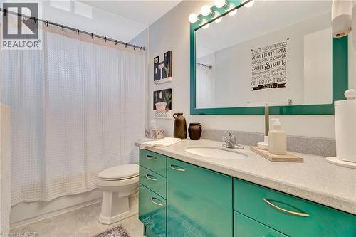 Bathroom featuring an elongated toilet, a vanity with teal cabinetry, a light-colored countertop, and an integrated sink basin - 98 Belwood Crescent, Kitchener, ON - Indoor Photo Showing Bathroom