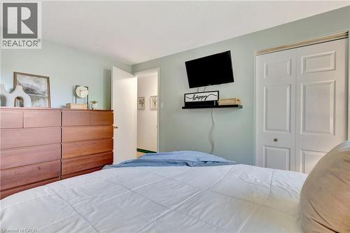 Room featuring light green wall paint and white trim, paneled bifold closet doors, a wall-mounted shelf, and a doorway with a white door - 98 Belwood Crescent, Kitchener, ON - Indoor Photo Showing Bedroom