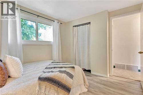 Room featuring light-colored wood-finish flooring, a window with white trim, and a white interior door with brass hardware - 98 Belwood Crescent, Kitchener, ON - Indoor Photo Showing Bedroom
