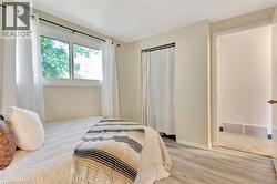 Room featuring light-colored wood-finish flooring, a window with white trim, and a white interior door with brass hardware - 