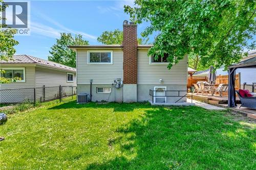 Spacious backyard featuring a lush lawn, a multi-level wood-finish deck, and an exterior basement entry with handrails - 98 Belwood Crescent, Kitchener, ON - Outdoor With Exterior