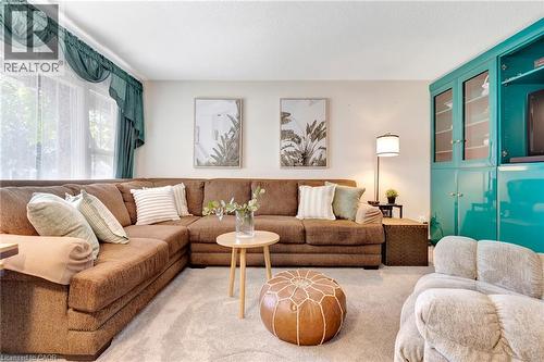 Bright room featuring a corner window with sheer and valance treatments, plush carpet flooring, and a built-in corner cabinet with glass-front doors - 98 Belwood Crescent, Kitchener, ON - Indoor Photo Showing Living Room