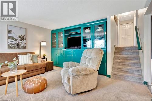 Built-in media center with glass-front cabinetry and vibrant teal finish - 98 Belwood Crescent, Kitchener, ON - Indoor Photo Showing Living Room