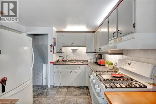 Kitchen featuring white cabinetry, tile backsplash, laminate countertops, and tile flooring - 98 Belwood Crescent, Kitchener, ON - Indoor Photo Showing Kitchen With Double Sink