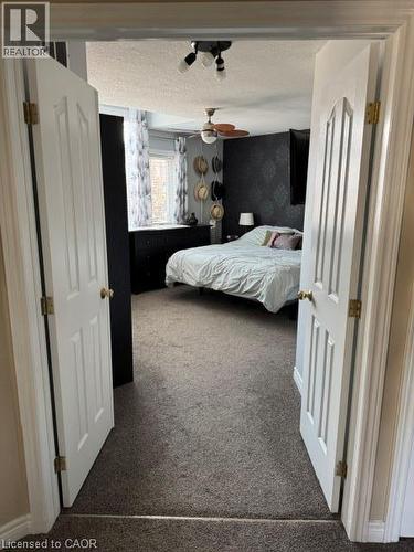 Bedroom featuring textured wall covering, a window with patterned curtains, and a ceiling fan with light fixture - 102 Willow Lane, Grimsby, ON - Indoor Photo Showing Bedroom