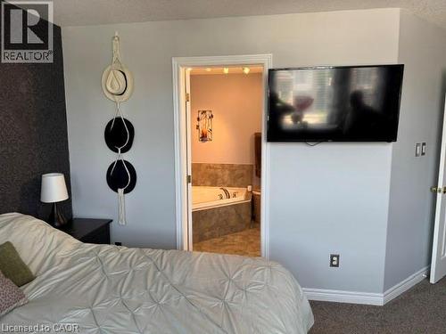 Bedroom area featuring light gray wall paint, a textured accent wall, and wood-finish trim - 102 Willow Lane, Grimsby, ON - Indoor Photo Showing Bedroom