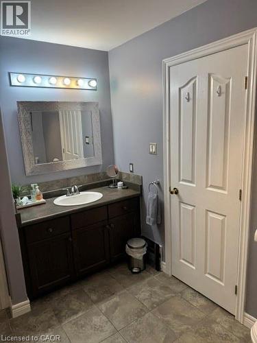 Bathroom featuring a single vanity with a white oval sink, dark cabinetry, and a dark countertop - 102 Willow Lane, Grimsby, ON - Indoor Photo Showing Bathroom