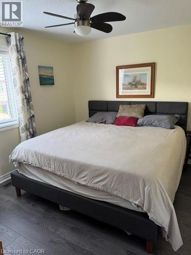 Bedroom featuring dark wood-finish flooring, a ceiling fan with integrated lighting, and a white framed window - 102 Willow Lane, Grimsby, ON - Indoor Photo Showing Bedroom