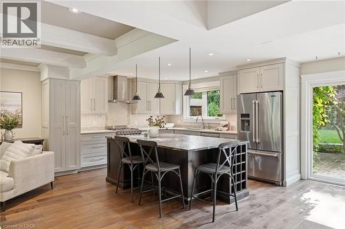 Open-concept kitchen featuring an oversized island with seating, stone countertops, stainless steel appliances, and wood-finish flooring - 266 Ferndale Place, Waterloo, ON - Indoor