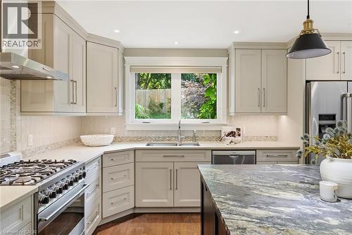 Contemporary kitchen featuring light-toned cabinetry, stainless steel appliances, a gas range with an overhead ventilation hood, a double basin sink, and a multi-toned island countertop - 266 Ferndale Place, Waterloo, ON - Indoor Photo Showing Kitchen With Upgraded Kitchen