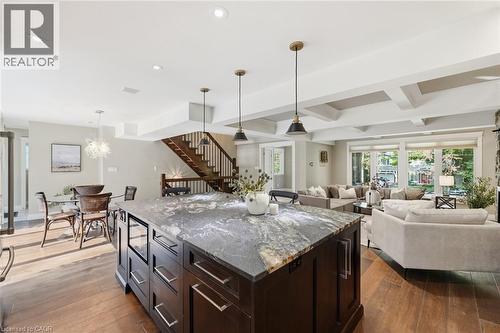 Gourmet kitchen island featuring a stone countertop, built-in beverage refrigerator, and dark wood cabinetry - 266 Ferndale Place, Waterloo, ON - Indoor Photo Showing Other Room